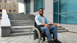 Photo of man in wheelchair stuck at bottom of steps with no ramp available.