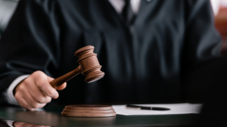 partial view of blurred judge in robe holding gavel in court