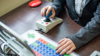 A woman using a specialized computer with a joy stick.