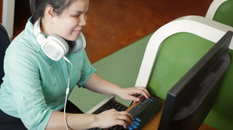 Blind girl using a computer with headphones and assistive technology.